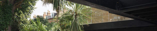 View from the inside of a house into a green patio and a terrace above, designed by Architecture:WK.