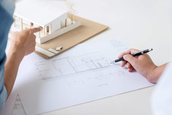 Image of an architect working on a blueprint for a new build home with their client.
